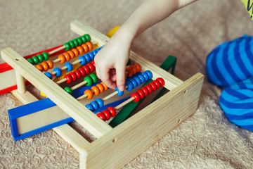 Preschooler baby learns to count. Cute child playing with abacus toy. Little boy having fun indoors...