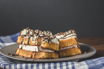 waffles with cream and chocolate on plate on wooden table, free space for text.