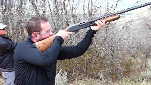 Slow motion of men shooting clay pigeons with a shotgun