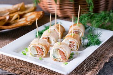 Tasty roll of pancakes with fish and cream cheese on plate
