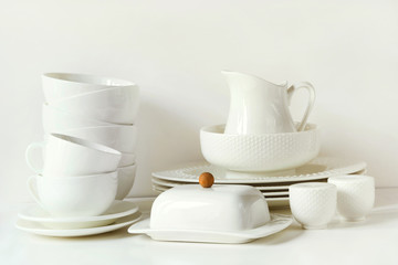 White tableware for serving. Crockery,dish, utensils and other different white stuff on white table-top. Kitchen still life as background. Copy space.