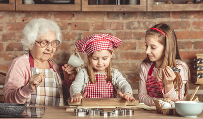 Grandma and granddaughters spreading dough