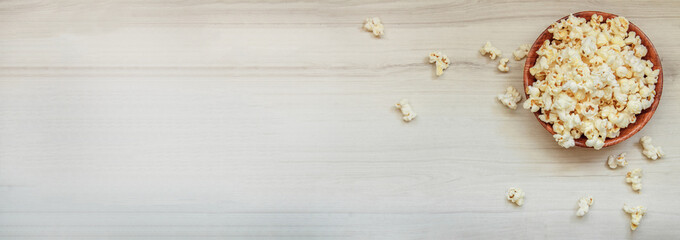 Salted popcorn on a wooden table. Banner for website, advertising - obrazy, fototapety, plakaty