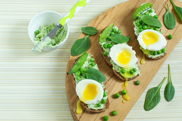 Toast to breakfast with cottage cheese and herbs, green peas, soft egg and spinach