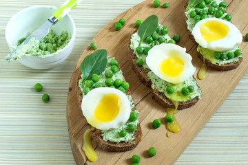 Toast to breakfast with cottage cheese and herbs, green peas, soft egg and spinach