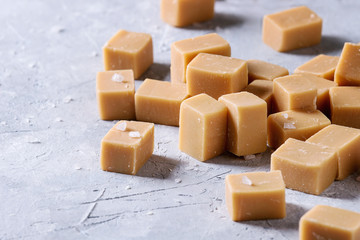 Salted caramel fudge candy over grey texture background. Close up, space