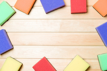 Multicolor cleaning sponges on wooden background copy space