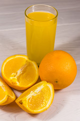 Glass of orange juice and fresh oranges on white wooden table