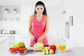 Beautiful indian woman cutting lettuce