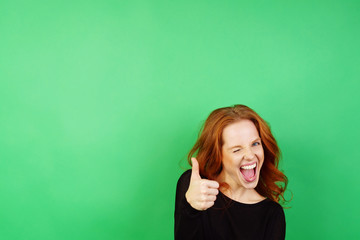 Cheerful woman giving thumb up on green background