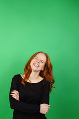 Fototapeta premium Young woman laughing against green background