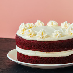 Red velvet cake with cream cheese frosting on a white plate