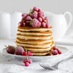 Stack of pancakes with raspberry, red currant, cream and honey on white table cloth © thayra83