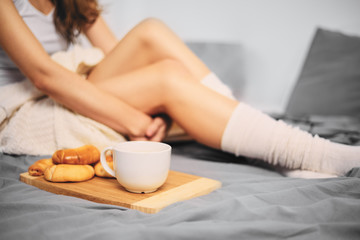 Obraz na płótnie Canvas Close up of woman`s legs on the bed. Cookies and cup of coffee next to legs.