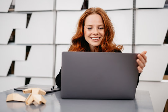 Young red-haired woman sitting in front of laptop