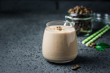 Mocha banana coffee breakfast smoothie and coffee beans in glass jar on dark concrete background....
