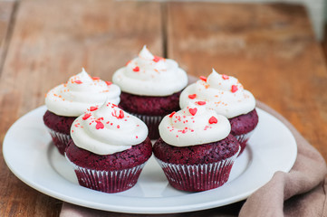 Red velvet cupcakes with cream cheese frosting on a white plate