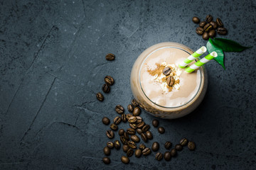 Creamy coffee breakfast smoothie and coffee beans on dark concrete background. Top view, space for...