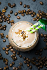 Healthy salted caramel mocha coffee smoothie and coffee beans on dark concrete background. Top view, space for text, close up, selective focus.