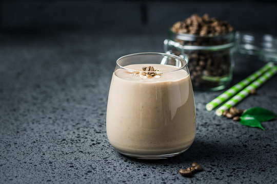 Mocha banana coffee breakfast smoothie and coffee beans in glass jar on dark concrete background. Selective focus, space for text. 