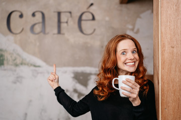 Portrait of cheerful redhead woman drinking coffee