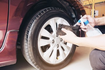 Fototapeta na wymiar Service man is waxing car tire garage - car maintenance service concept