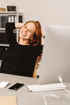 Happy woman sitting at desk in a modern office