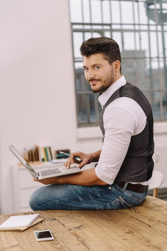 Young smiling man with laptop in office