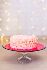 birthday or anniversary concept - pink cake over brick background with lights