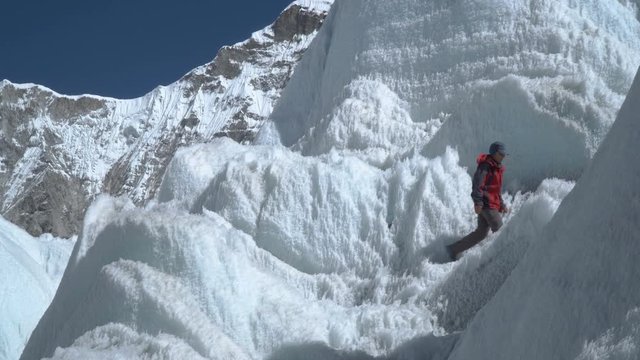 The Khumbu Glacier descends from Mount Everest. Walking on the glacier is very dangerous. The girl climbs the glacier. Nepal. Himalayas. 4K