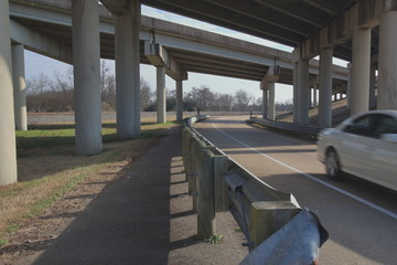 Curving road under  a highway overpass with a speeding vehicle