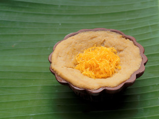 Thai dessert, egg custard with sweet sticky rice topped with golden threads, on banana leaf background
