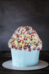 Birthday cake with icing flowers on gray background. Mother's Day, first birthday. Celebration concept. Vertical.