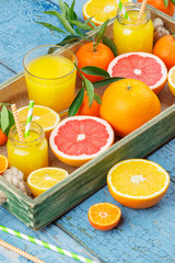 Different fruits and glass with fresh orange juice, wooden background