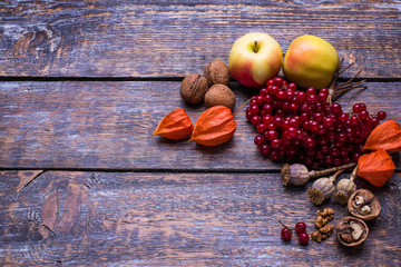 Autumn leaves, walnuts, apples, viburnum, physalis on a wooden background