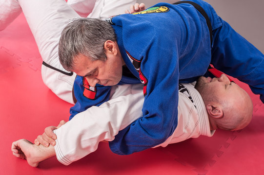 Brazilian jiu jitsu instructor demonstrates ground fighting arm lock techniques
