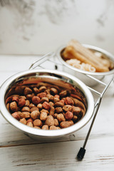 Bowls with dry dog food and chew bones on a white board background. Pet care and veterinary concept