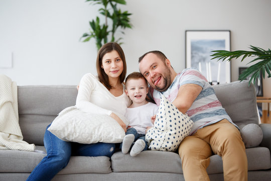 Photo of happy parents with son on gray sofa