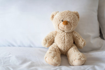 Sleeping teddy bear on white bed