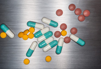 Pharmaceutical and vitamin pills on brushed metal background texture