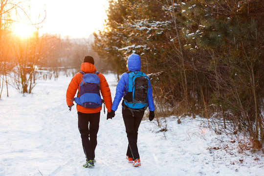 Romantic photo from back of man and woman with backpacks in winter forest