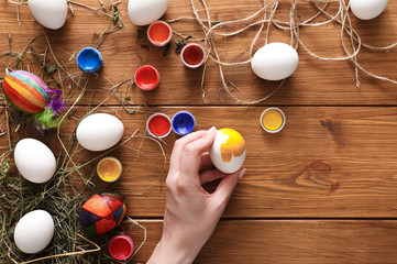 Painting colorful easter eggs, top view on wood