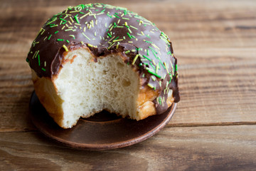 bitten donut with chocolate on a wooden background