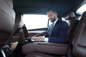 Fototapeta na wymiar smiling businessman sitting in the back seat of a prestigious car