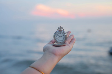 pocket watch in hand on sea scape background.