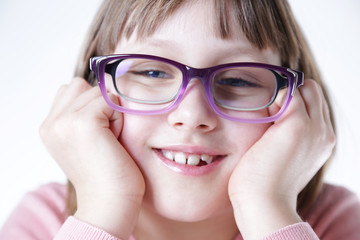 Dziewczynka trzyma kolorowe oprawki okularów.  © doroguzenda