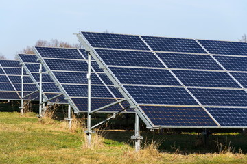 Blue solar panels in photovoltaics power station farm with trees in background, future innovation energy concept, clear blue sky background, Czech Republic