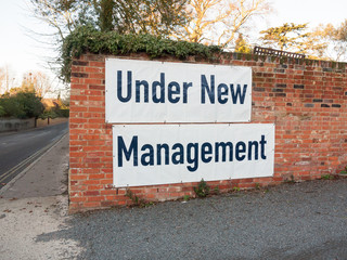 big large white and black sign on brick wall under new management