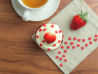 Top-view (high angle) image of red velvet strawberry cup cake with strawberry, tea cup and heart shape sugar on wooden background, Valentine concept, Copy space