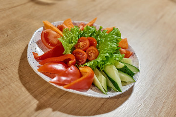 Plate with fresh vegetables.Fresh vegetable vitamin salad in plate on wooden table